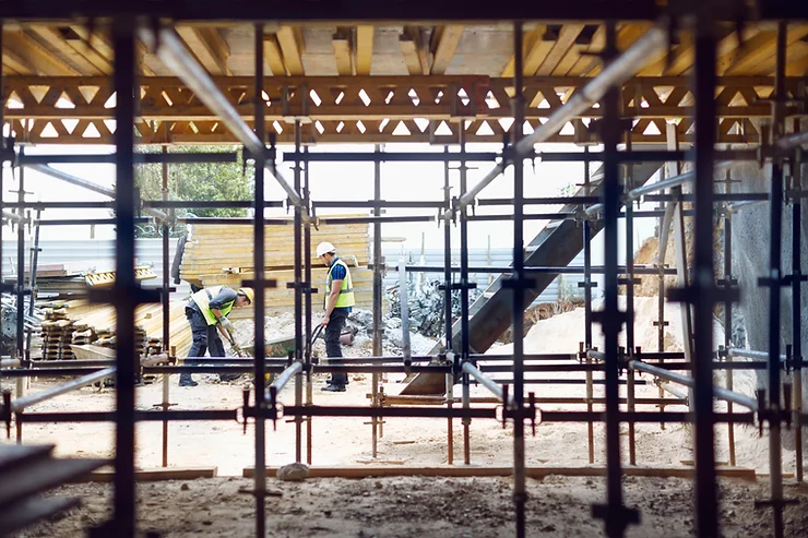 Two construction workers working together in a safe manner